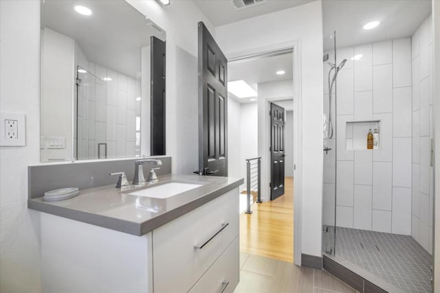 bathroom featuring vanity, wood-type flooring, and a shower with shower door