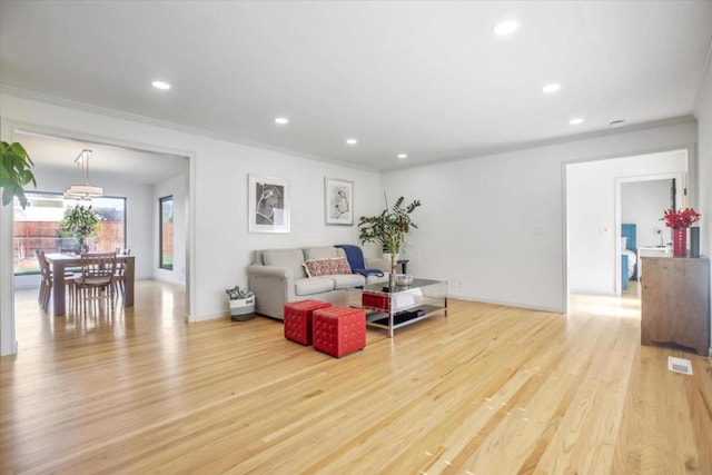 living room with crown molding and light wood-type flooring