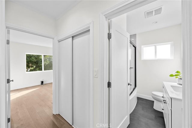 full bathroom featuring vanity, hardwood / wood-style floors, enclosed tub / shower combo, and toilet