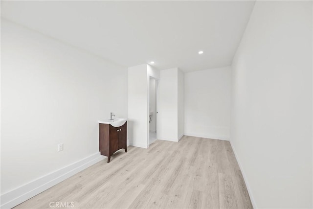 spare room featuring sink and light wood-type flooring