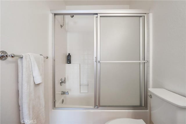 bathroom featuring shower / bath combination with glass door and toilet