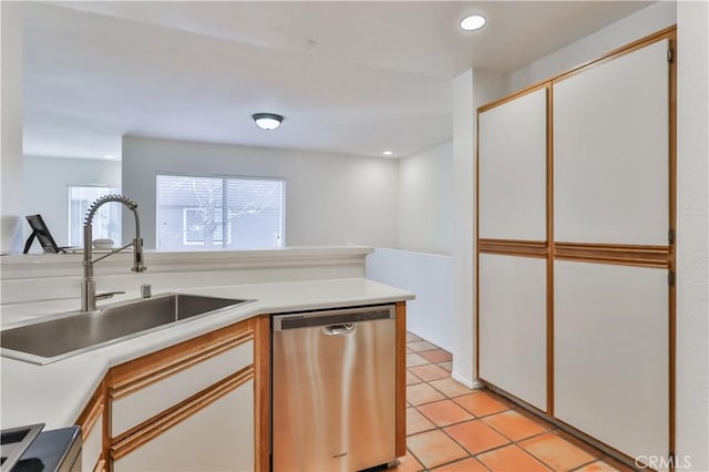 kitchen with white cabinetry, stainless steel dishwasher, light tile patterned flooring, and sink