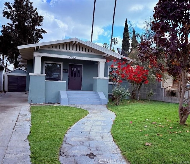 bungalow-style house with a porch, a garage, an outdoor structure, and a front yard