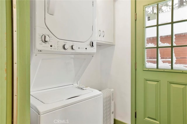 washroom featuring cabinets and stacked washing maching and dryer