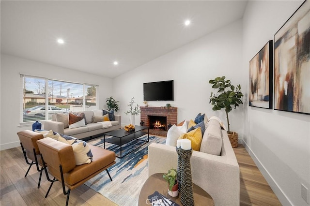 living room with lofted ceiling, a fireplace, and light hardwood / wood-style flooring