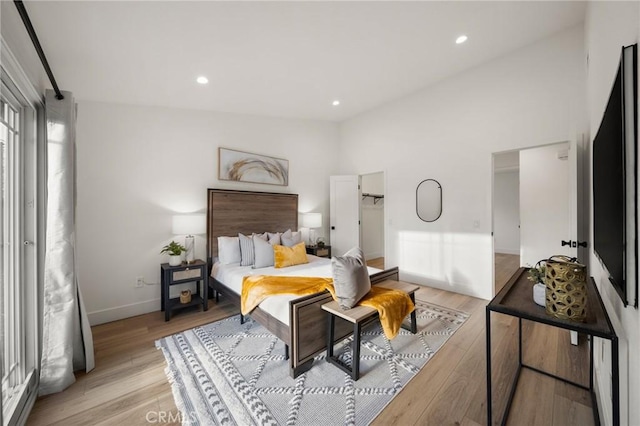 bedroom with high vaulted ceiling and light hardwood / wood-style flooring