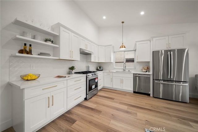 kitchen featuring sink, white cabinetry, pendant lighting, stainless steel appliances, and light hardwood / wood-style floors