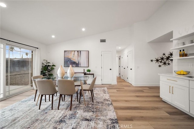 dining area with lofted ceiling and light hardwood / wood-style flooring