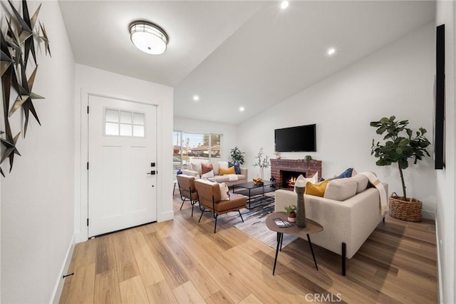 living room featuring a fireplace, light hardwood / wood-style floors, and vaulted ceiling