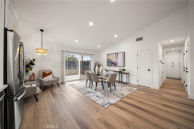 dining space featuring high vaulted ceiling, a notable chandelier, and light wood-type flooring