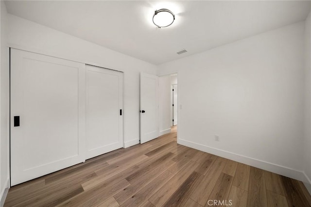 unfurnished bedroom with light hardwood / wood-style flooring and a closet