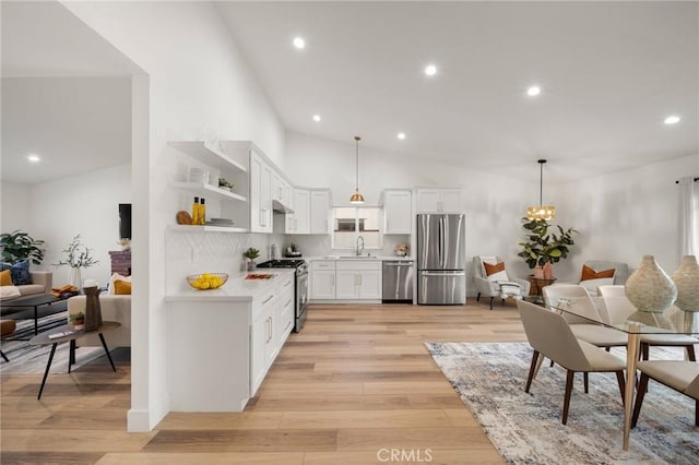 kitchen with white cabinetry, sink, hanging light fixtures, stainless steel appliances, and light hardwood / wood-style flooring