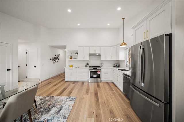 kitchen with sink, high vaulted ceiling, hanging light fixtures, appliances with stainless steel finishes, and white cabinets