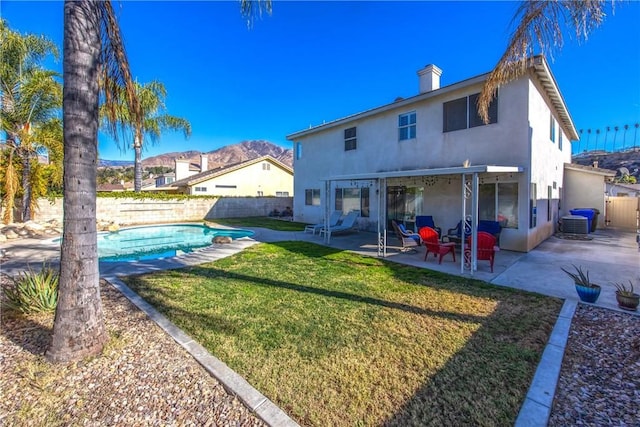 back of house with a fenced in pool, a patio, and a lawn