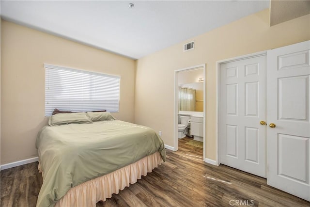 bedroom with ensuite bathroom and dark hardwood / wood-style flooring