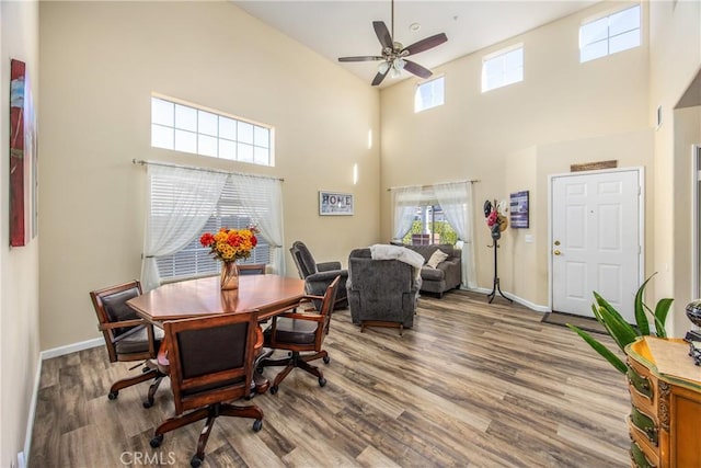 dining room featuring hardwood / wood-style flooring, ceiling fan, and a towering ceiling