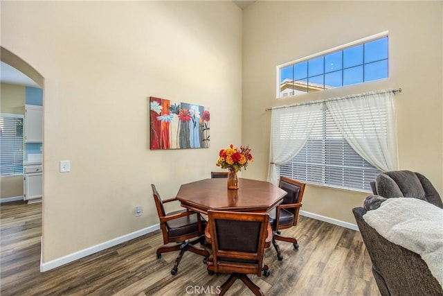 dining area featuring dark wood-type flooring and a towering ceiling