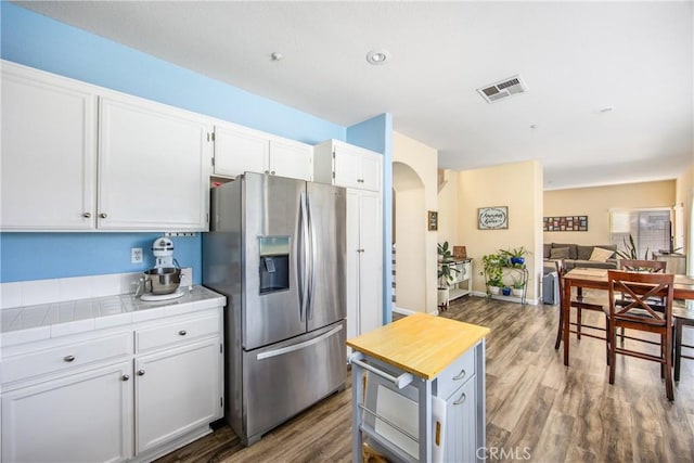 kitchen featuring stainless steel refrigerator with ice dispenser, wood-type flooring, tile countertops, and white cabinets