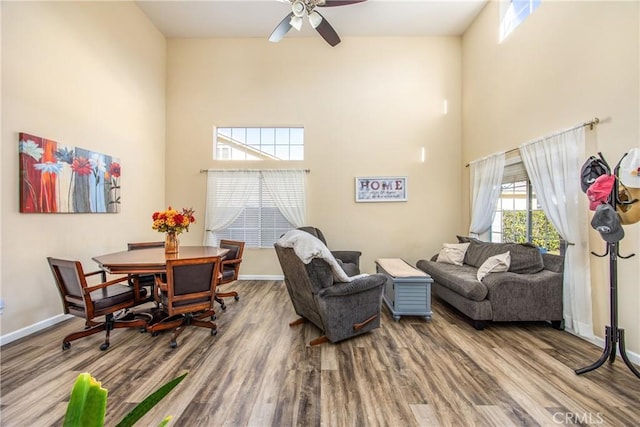 living room with ceiling fan, hardwood / wood-style floors, and a high ceiling