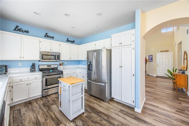 kitchen with stainless steel appliances, white cabinetry, a center island, and dark wood-type flooring