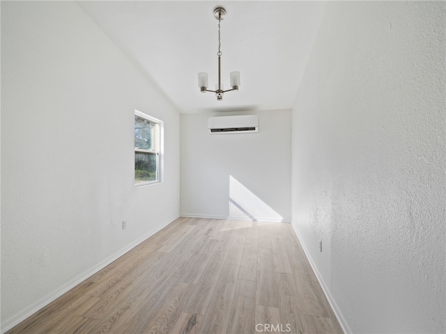 unfurnished room featuring a chandelier, a wall unit AC, and light hardwood / wood-style floors