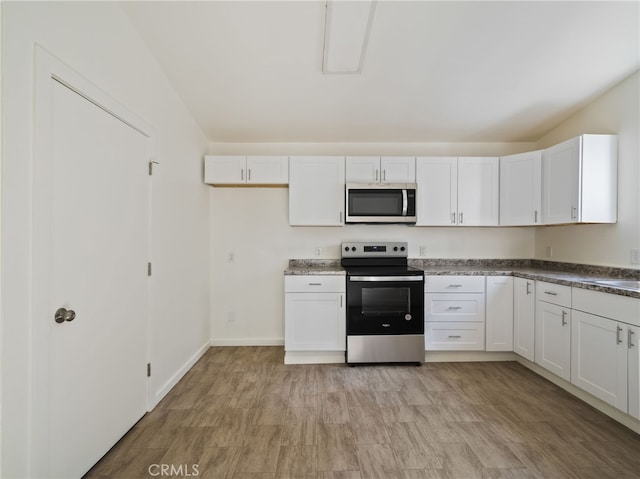 kitchen with stainless steel appliances, light hardwood / wood-style floors, and white cabinets