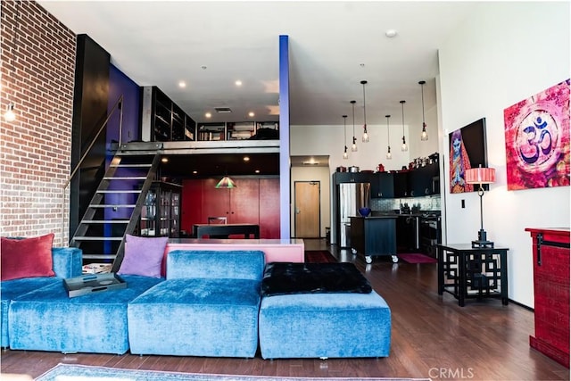 living room featuring dark wood-style floors, brick wall, and a high ceiling