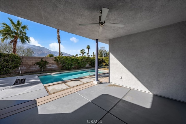 view of swimming pool with ceiling fan, a mountain view, and a patio area