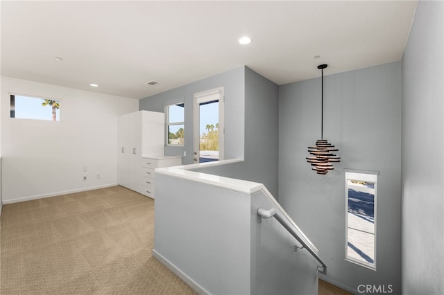 hall featuring plenty of natural light and light colored carpet