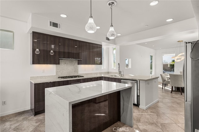 kitchen with sink, hanging light fixtures, a center island, light stone counters, and stainless steel appliances