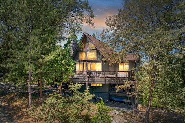 back house at dusk featuring a wooden deck