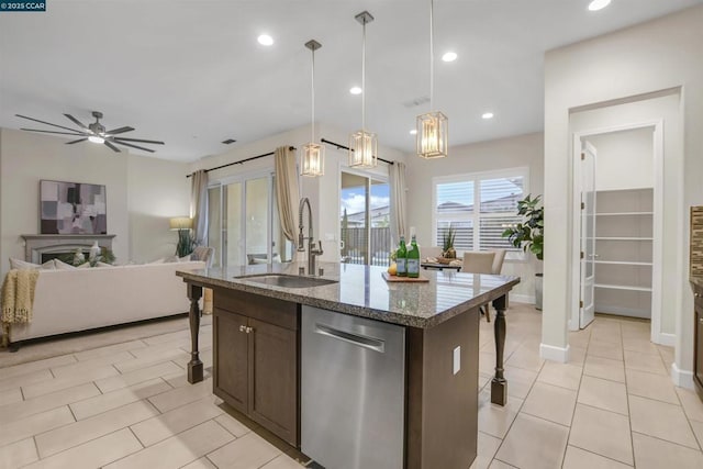 kitchen featuring pendant lighting, a breakfast bar area, stainless steel dishwasher, light stone counters, and a center island with sink