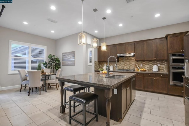 kitchen featuring sink, dark brown cabinets, hanging light fixtures, an island with sink, and stainless steel appliances