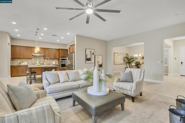 tiled living room with sink and ceiling fan with notable chandelier