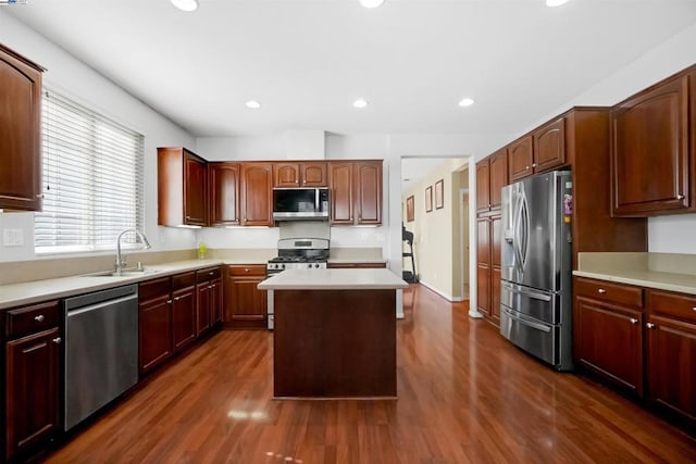 kitchen with a kitchen island, appliances with stainless steel finishes, sink, and dark wood-type flooring