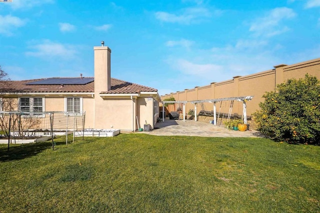 back of property with a patio, a yard, and solar panels