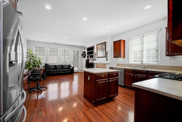 kitchen with a kitchen island, appliances with stainless steel finishes, sink, and dark hardwood / wood-style flooring