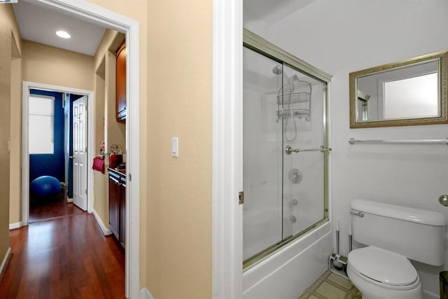 bathroom featuring toilet and combined bath / shower with glass door