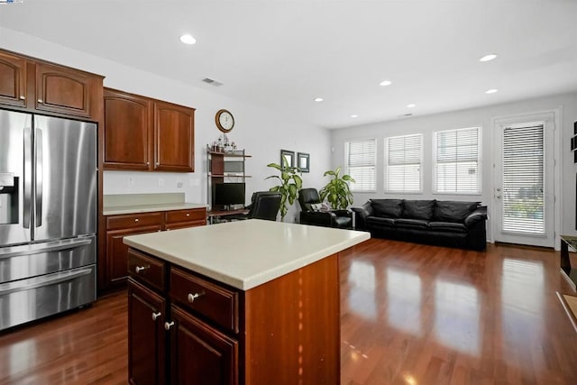 kitchen with stainless steel refrigerator with ice dispenser, a center island, and dark wood-type flooring