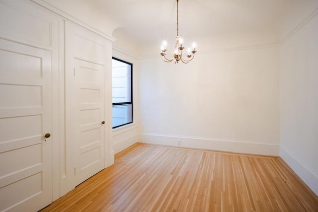 unfurnished room featuring an inviting chandelier and light wood-type flooring