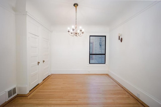 spare room with an inviting chandelier and hardwood / wood-style flooring