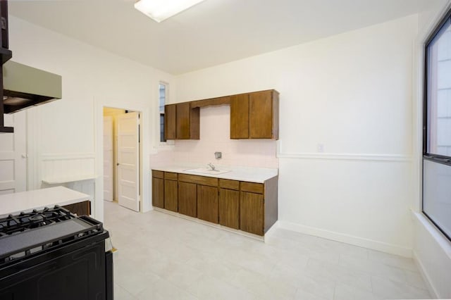 kitchen featuring black range with gas cooktop, extractor fan, sink, and decorative backsplash