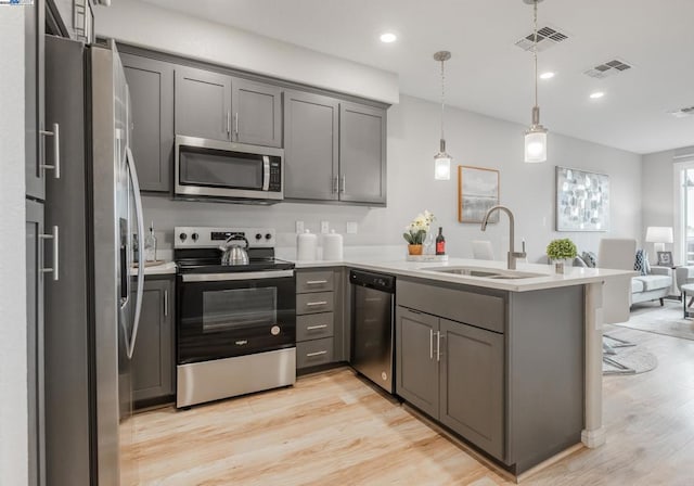 kitchen with sink, appliances with stainless steel finishes, gray cabinetry, decorative light fixtures, and kitchen peninsula