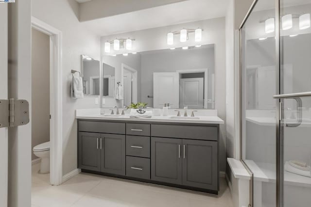 bathroom featuring a shower with door, vanity, tile patterned flooring, and toilet