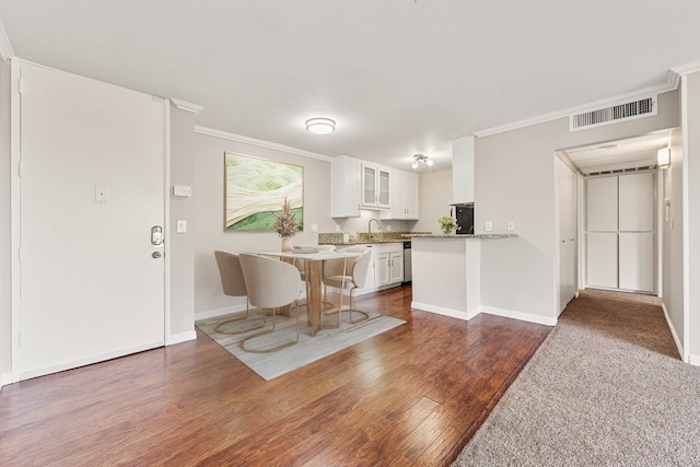 kitchen with sink, white cabinetry, ornamental molding, dark hardwood / wood-style flooring, and kitchen peninsula