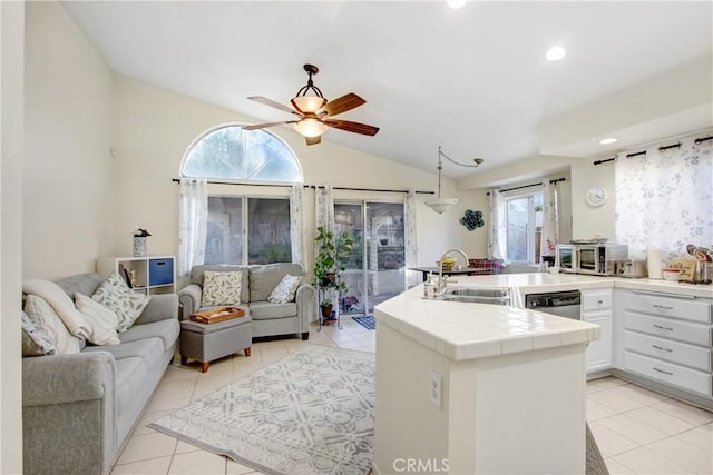 kitchen with sink, stainless steel dishwasher, tile counters, kitchen peninsula, and white cabinets