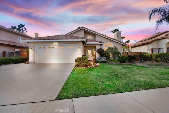 mediterranean / spanish-style house featuring a garage and a lawn