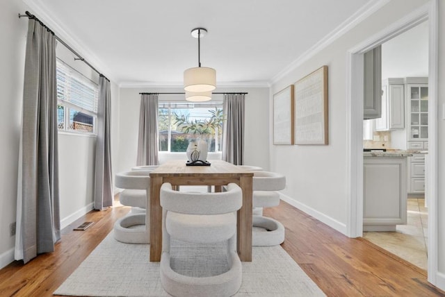 dining room with ornamental molding and light hardwood / wood-style floors