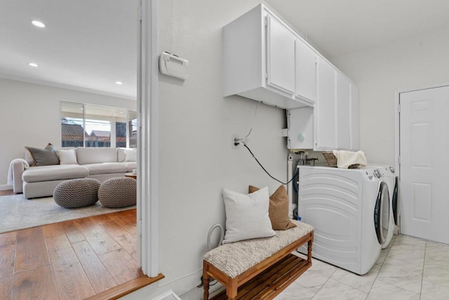 laundry room with cabinets, ornamental molding, and separate washer and dryer