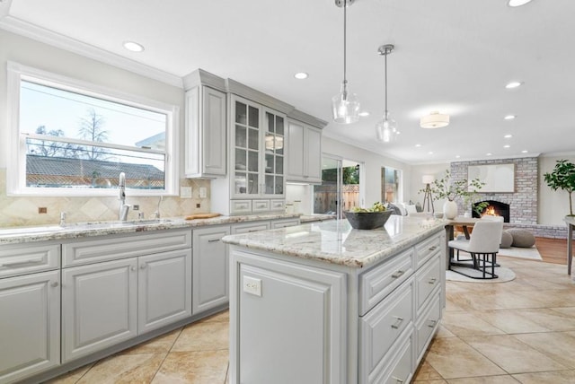 kitchen featuring hanging light fixtures, crown molding, a fireplace, and a kitchen island